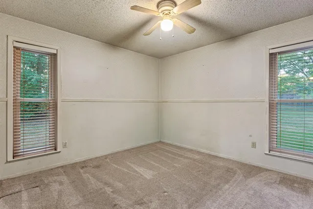 an empty room with a window and a fan