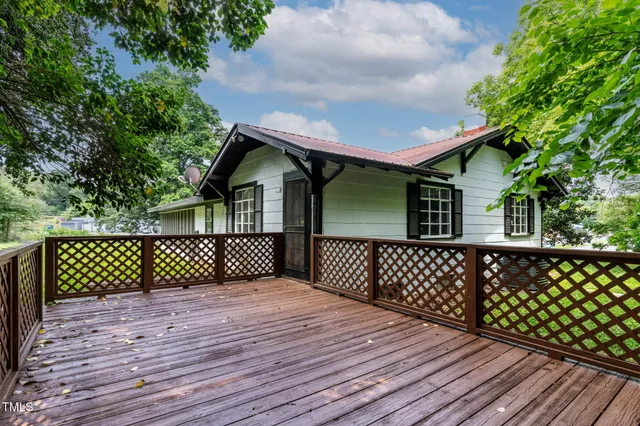 a backyard of a house with plants and large tree