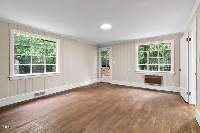 an empty room with wooden floor & windows closet and windows