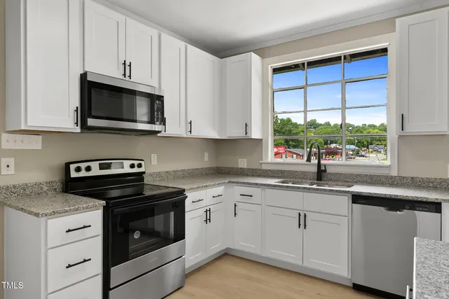 a kitchen with white cabinets stainless steel appliances and a sink
