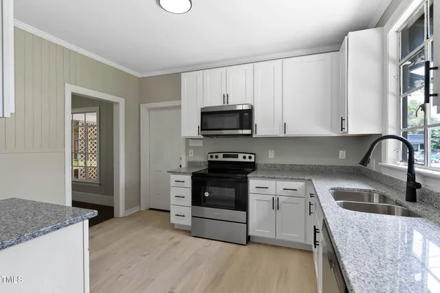 a kitchen with granite countertop white cabinets and stainless steel appliances