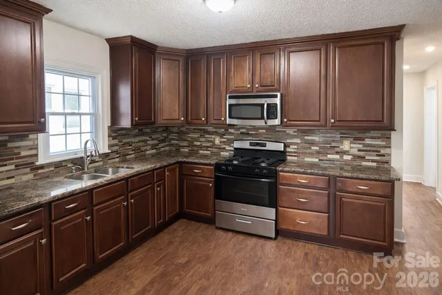 a kitchen with stainless steel appliances granite countertop a stove microwave and sink