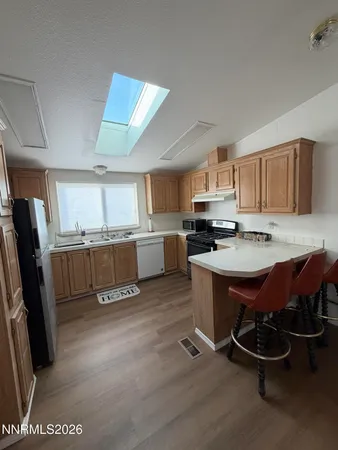 a open kitchen with stainless steel appliances granite countertop a refrigerator dining table and chairs