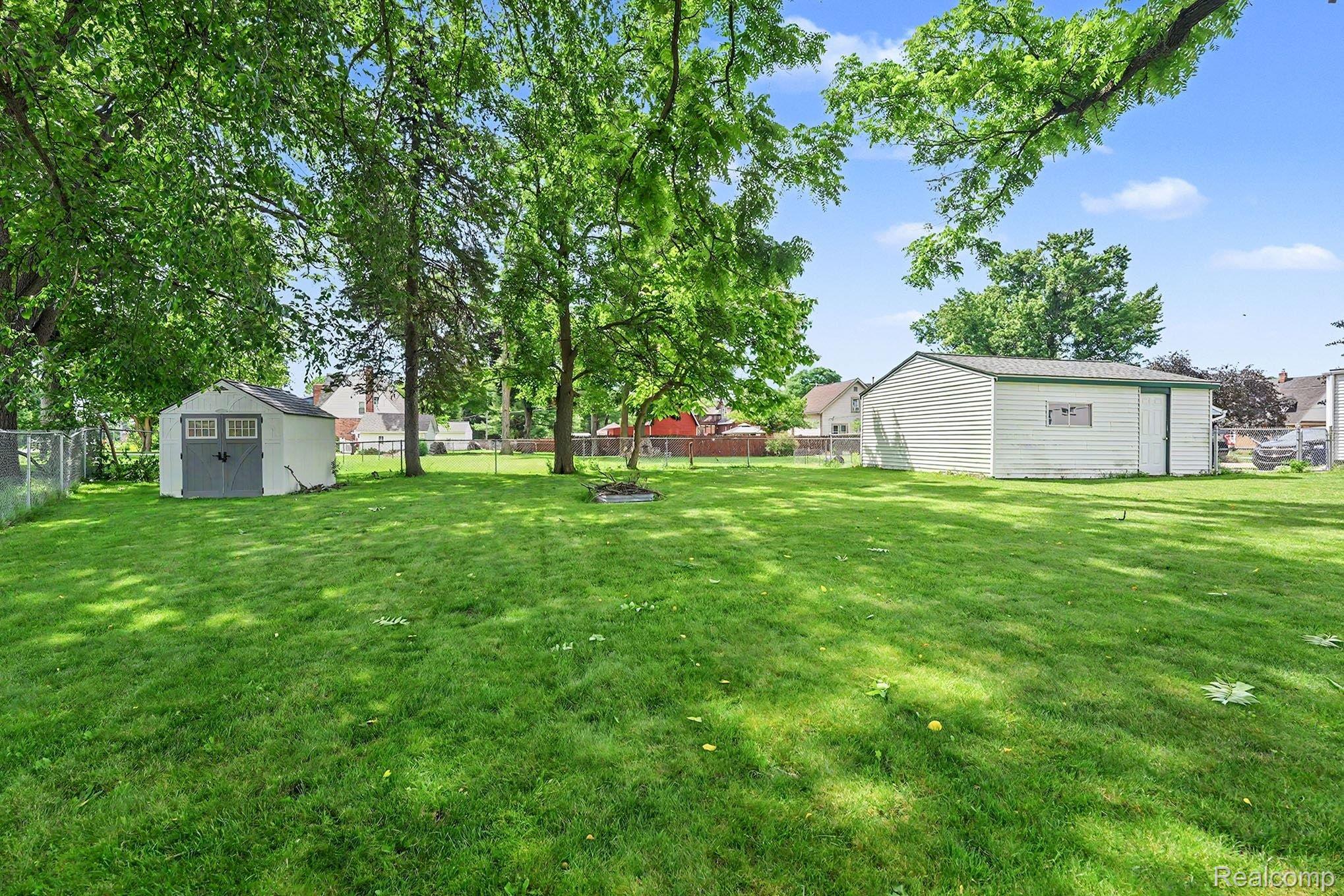 8215 Clinton River Road Sterling Heights, MI 48314 - Photo 24 of 28 Expansive grassy lawn with mature trees and two outbuildings
