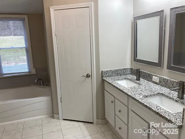 a bathroom with a granite countertop sink and a bathtub