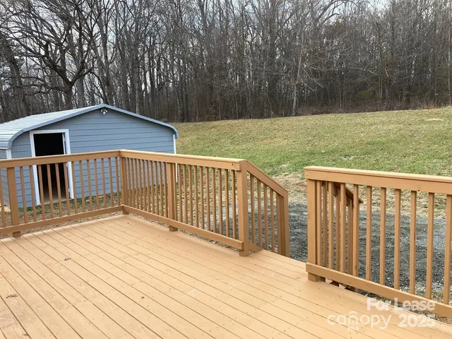 a view of backyard with deck and large trees