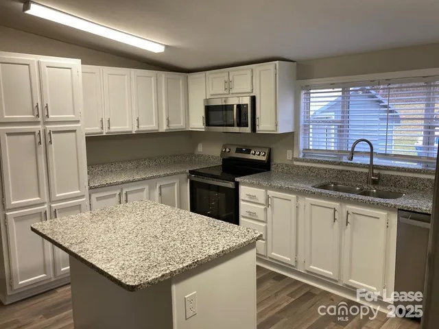 a kitchen with stainless steel appliances granite countertop a sink stove and cabinets