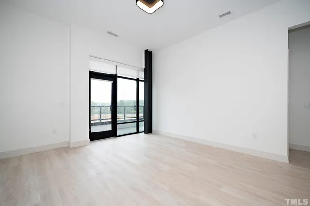 a view of an empty room with wooden floor and windows