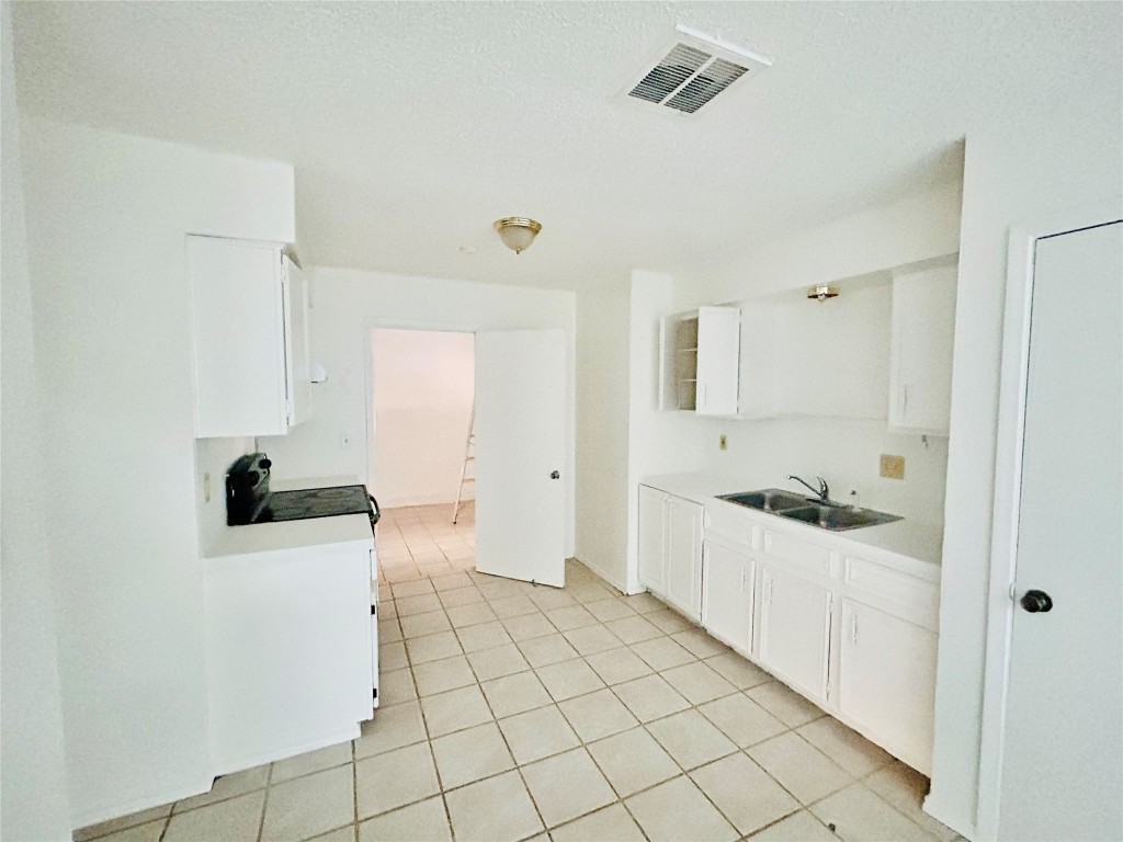 2305 South Bagdad Road Leander, TX 78641 - Photo 4 of 8 Kitchen with white cabinetry, light countertops, light tile patterned floors, black / electric stove, and a textured ceiling