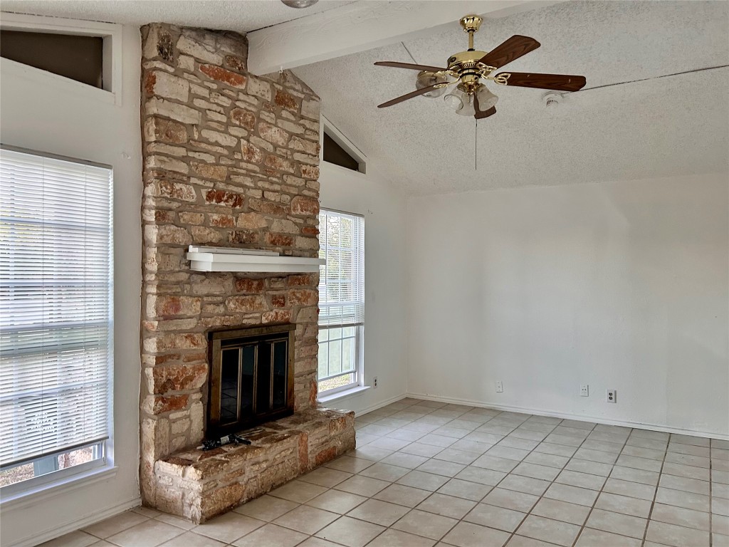 2305 South Bagdad Road Leander, TX 78641 - Photo 5 of 8 Unfurnished living room with a textured ceiling, tile patterned floors, ceiling fan, and a stone fireplace