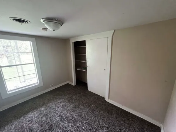 an empty room with windows and closet