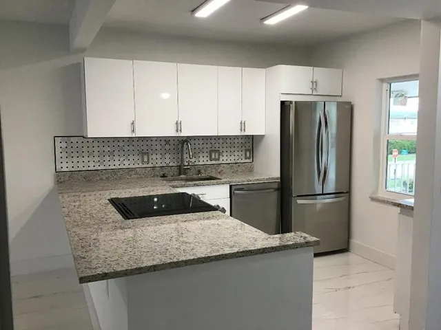 a kitchen with granite countertop a refrigerator sink and stove