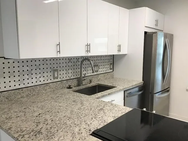 a kitchen with stainless steel appliances granite countertop a refrigerator a sink and a stove