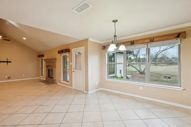 a view of an empty room with window and chandelier fan