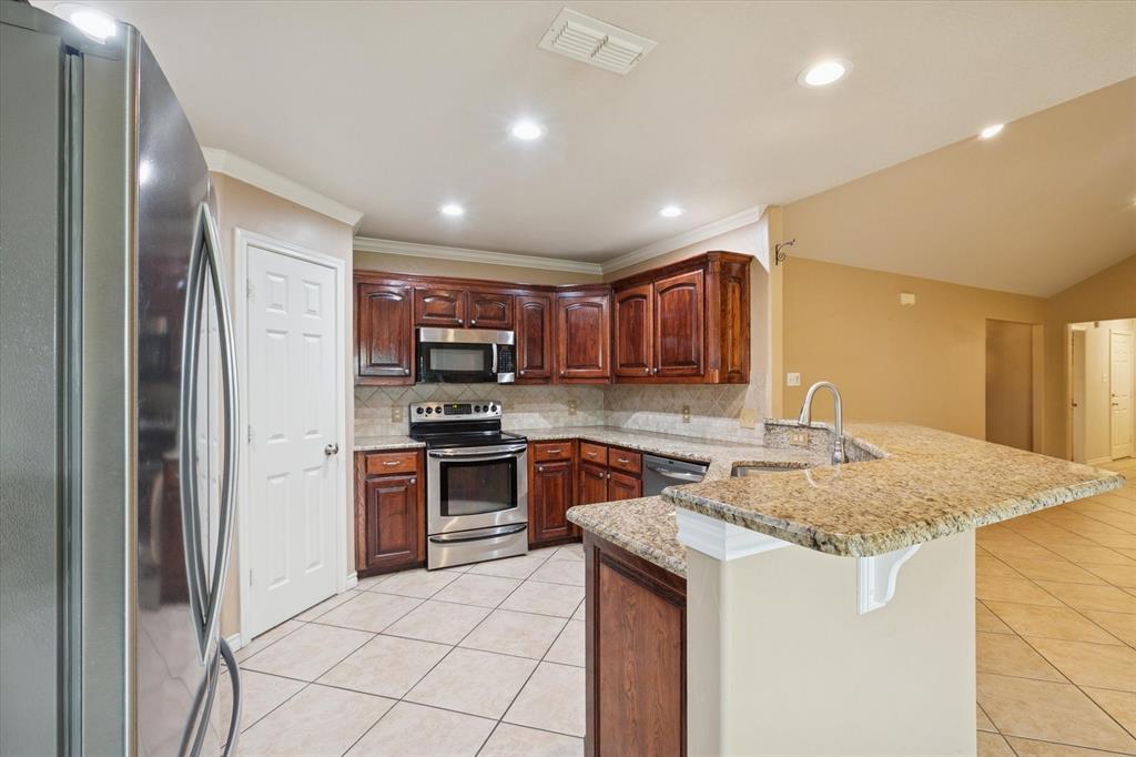 548 Highland Road Springtown, TX 76082 - Photo 15 of 40 a kitchen with stainless steel appliances granite countertop a sink stove and refrigerator