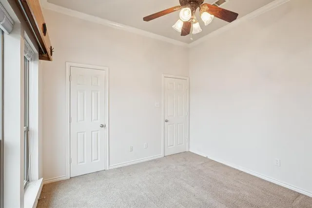 an empty room with a chandelier fan and windows