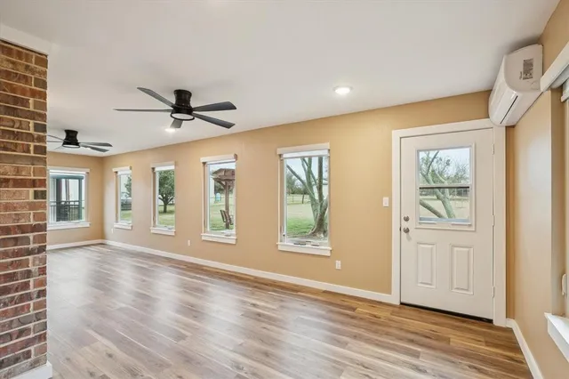 a view of an empty room with a window and wooden floor