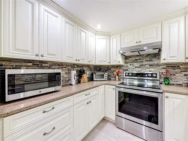 a kitchen with stainless steel appliances granite countertop a stove a sink and white cabinets