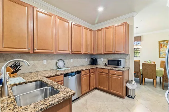 a kitchen with stainless steel appliances granite countertop wooden cabinets a sink and dishwasher a stove with wooden floor