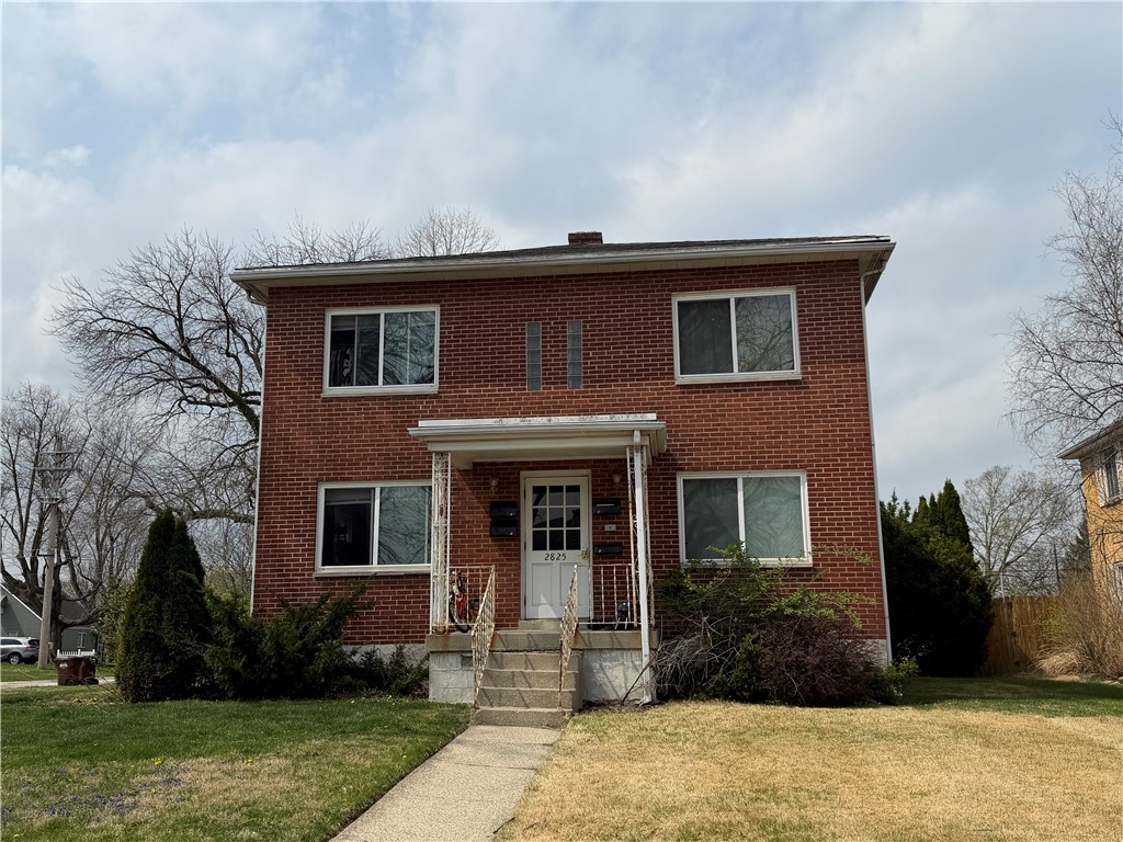 This classic brick residence offers a welcoming facade with a covered entry and mature landscaping.