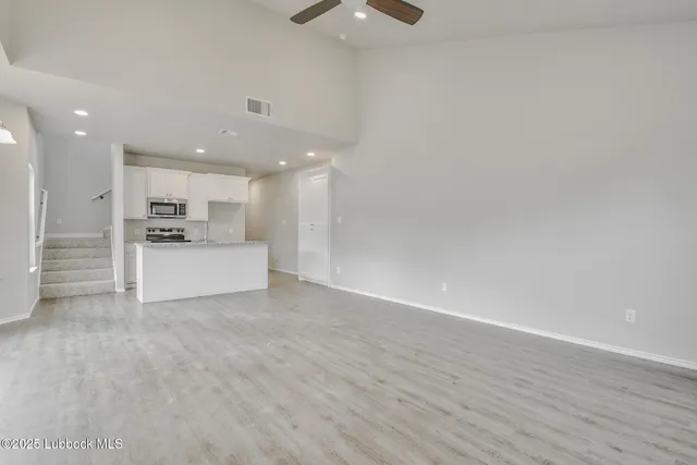 a view of kitchen with refrigerator and white cabinets