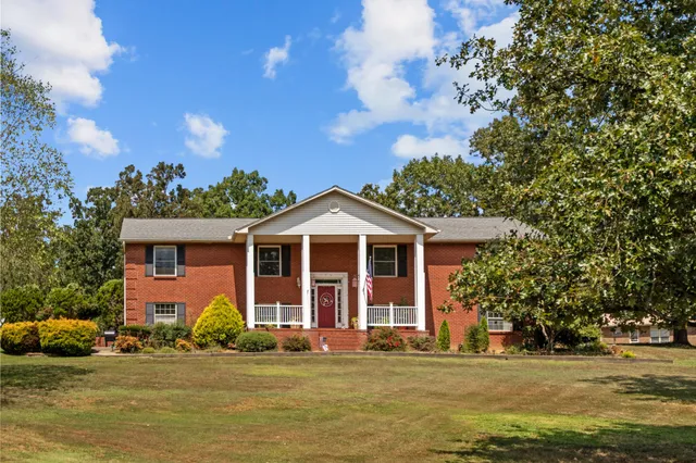 a front view of a house with a garden and trees