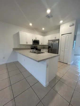 a kitchen with kitchen island granite countertop a stove a sink a refrigerator a microwave and cabinets