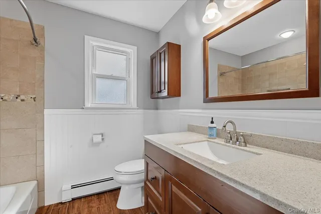 a bathroom with a granite countertop toilet sink and mirror