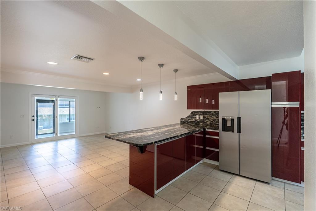 11001 Southeast Sunset Harbor Road, Unit 34 Summerfield, FL 34491 - Photo 4 of 31 Kitchen with kitchen peninsula, stainless steel fridge, tasteful backsplash, light tile flooring, and decorative light fixtures