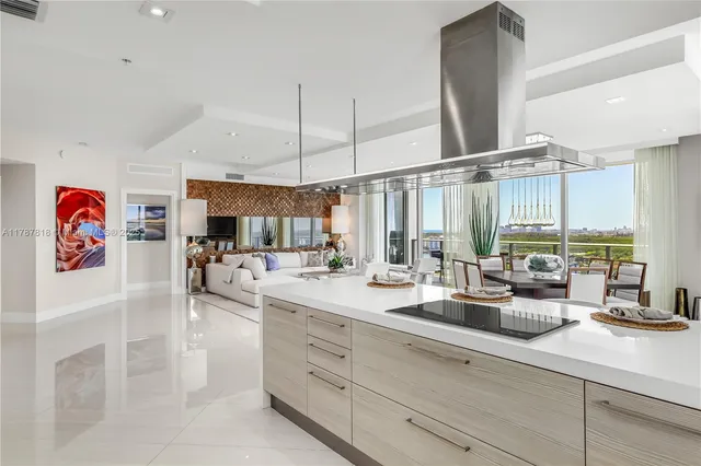 a kitchen with stainless steel appliances kitchen island granite countertop a table chairs and a refrigerator