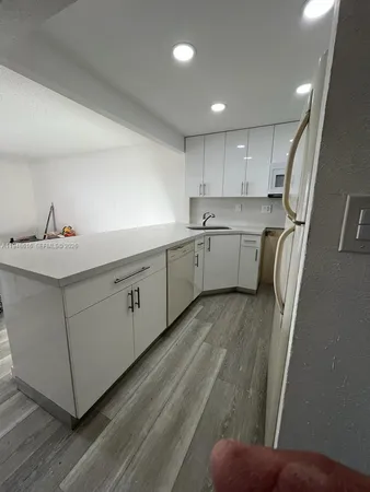 a kitchen with white cabinets and sink