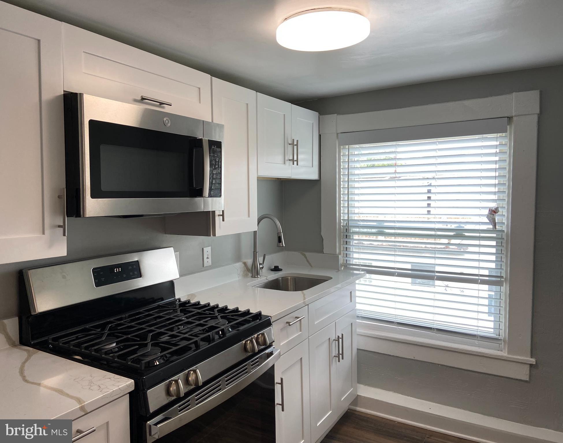 3414 Garrison Boulevard, Unit 3 Baltimore, MD 21215 - Photo 6 of 12 a kitchen with stainless steel appliances a sink stove and microwave