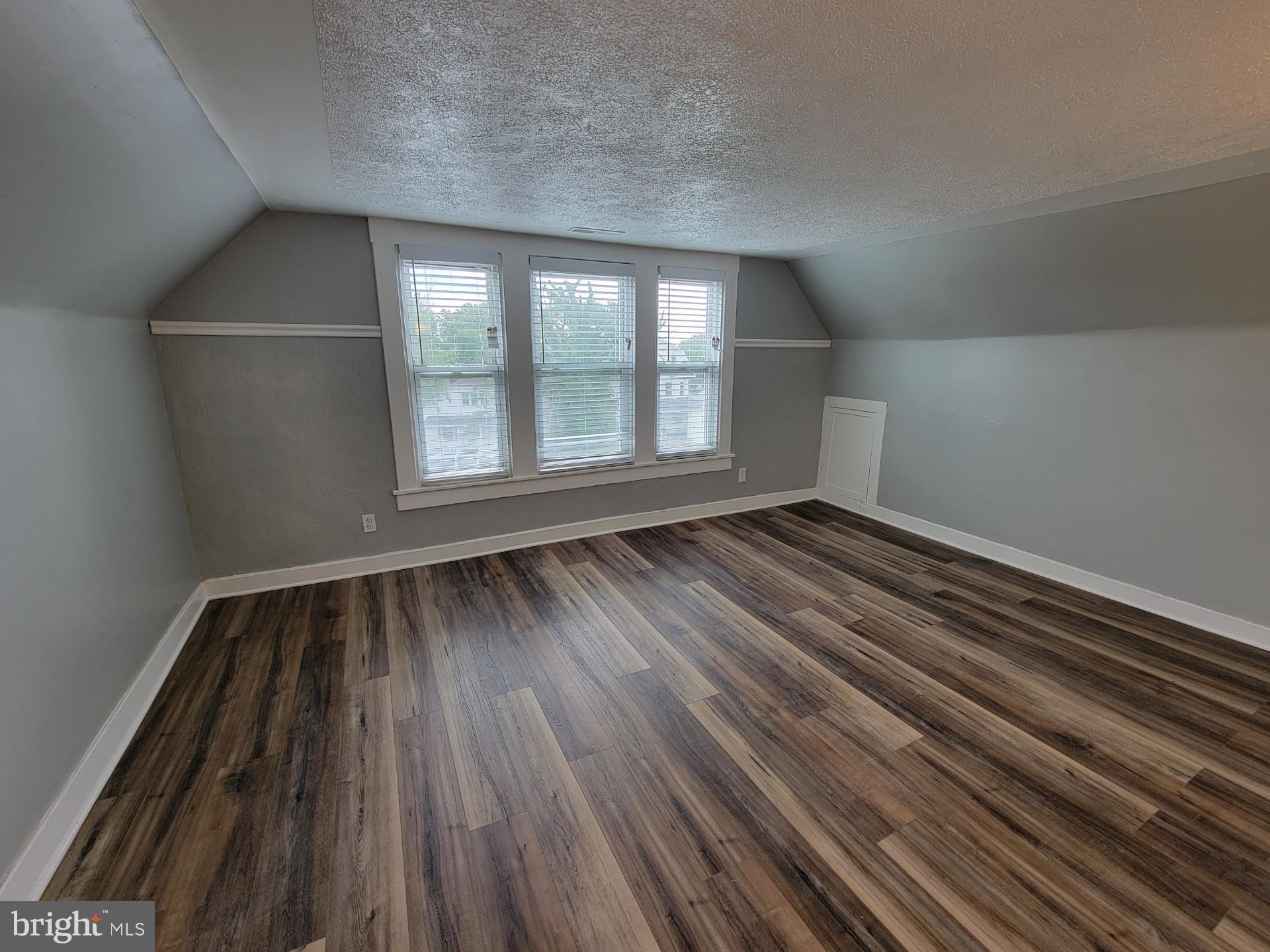 3414 Garrison Boulevard, Unit 3 Baltimore, MD 21215 - Photo 7 of 12 an empty room with wooden floor and windows