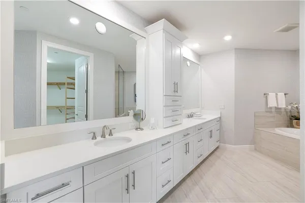a bathroom with a double vanity sink mirror double and bathtub