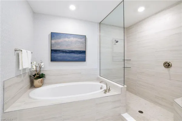 a white bath tub sitting next to a white sink and vanity
