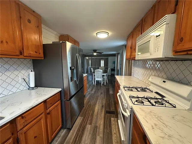 a kitchen with stainless steel appliances granite countertop a refrigerator a stove and a wooden cabinets