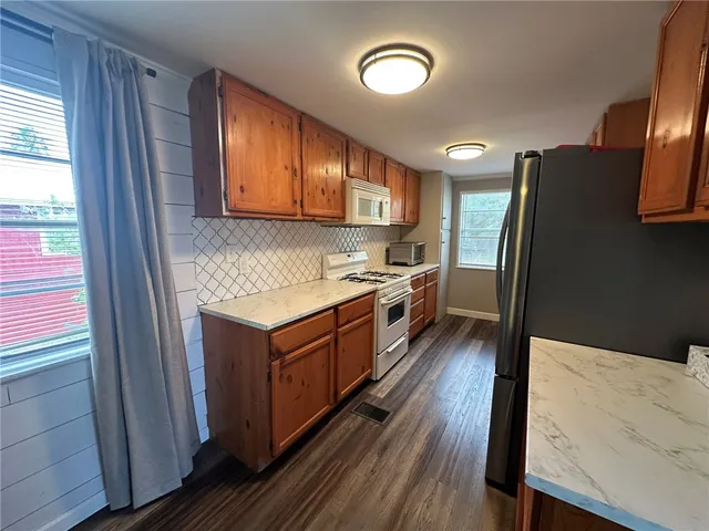 a kitchen with stainless steel appliances granite countertop a stove a refrigerator a sink dishwasher and wooden cabinets with wooden floor