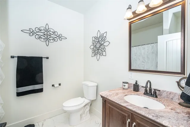 a bathroom with a granite countertop toilet sink and mirror