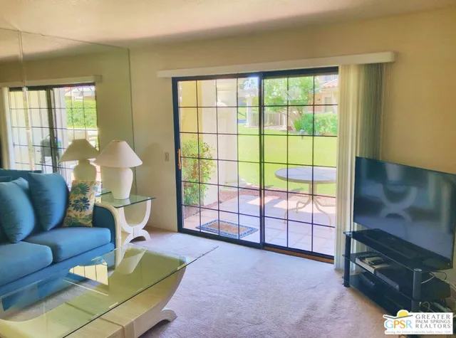 a living room with furniture a flat screen tv and a floor to ceiling window