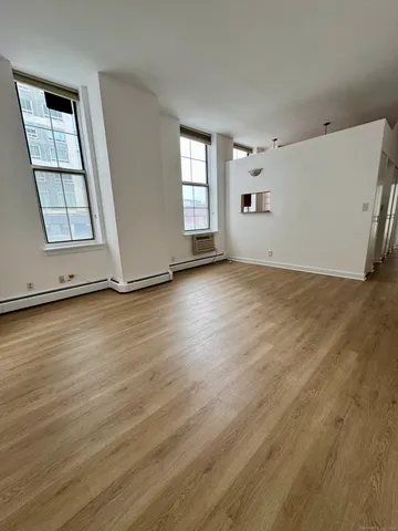 an empty room with wooden floor and window