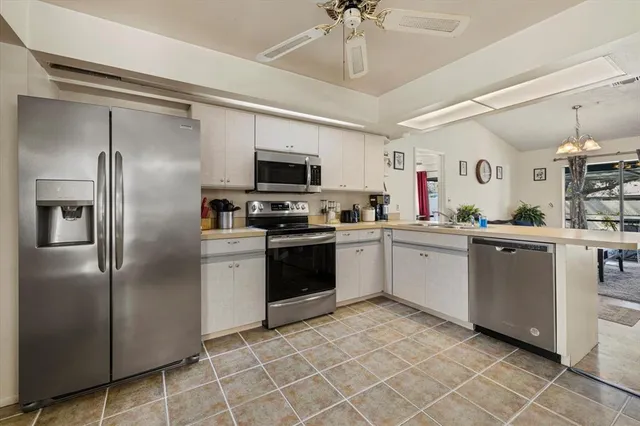 a open kitchen with stainless steel appliances granite countertop a stove top oven a sink a dining table and chairs with wooden floor