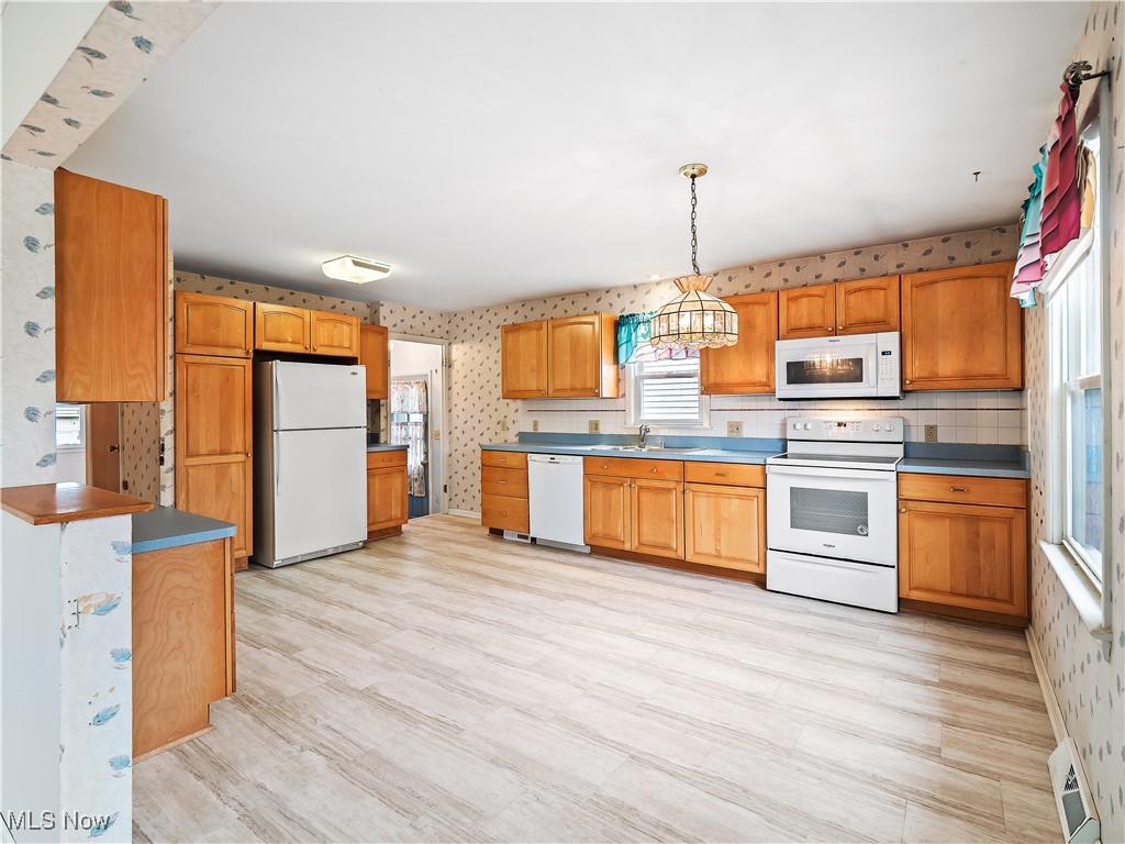 23812 Knickerbocker Road Bay Village, OH 44140 - Photo 10 of 31 Kitchen with pendant lighting, white appliances, sink, and light wood-type flooring