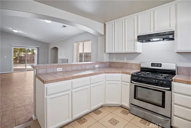 a kitchen with granite countertop a stove sink and cabinets