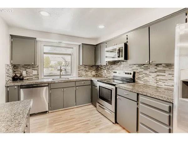 a kitchen with stainless steel appliances granite countertop a sink stove and cabinets