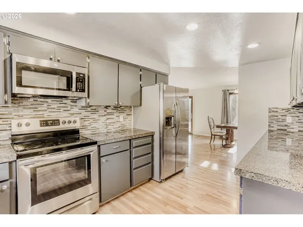 a kitchen with stainless steel appliances kitchen island granite countertop a stove a refrigerator and a microwave