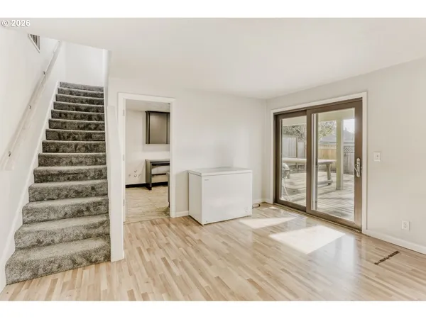 a view of an empty room with wooden floor and windows