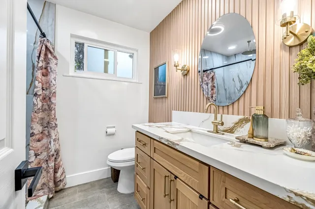a bathroom with a granite countertop sink toilet and mirror