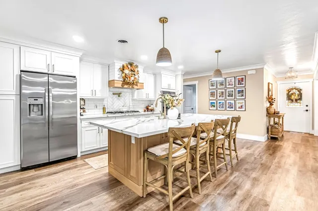 a kitchen with stainless steel appliances granite countertop a stove a refrigerator a oven a dining table and chairs with wooden floor