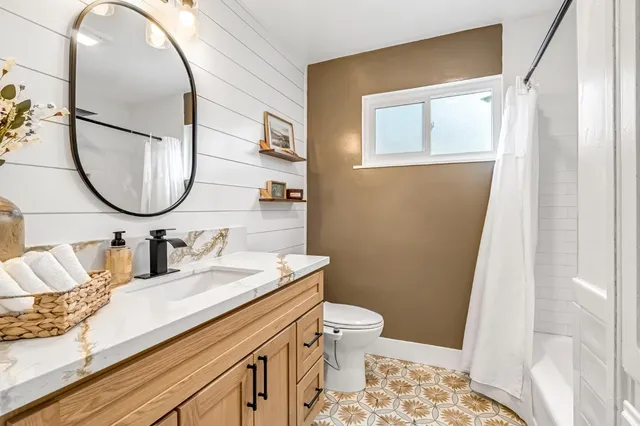 a bathroom with a granite countertop sink mirror vanity and toilet