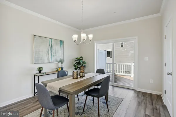 a dining room with furniture wooden floor a rug a potted plant and a chandelier